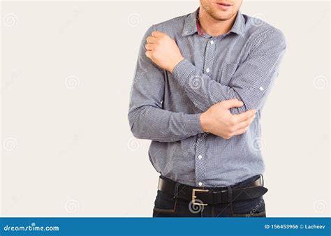 A Man Holds An Elbow With His Hand On A Gray Background Stock Photo