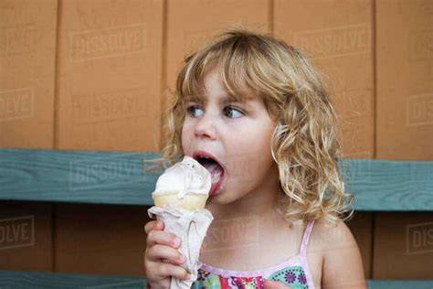 Close Up Of Babe Girl Eating Ice Cream On Bench Stock Photo Dissolve