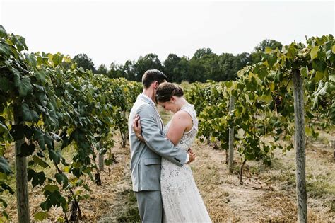 A Bride And Groom Standing In The Middle Of A Vineyard