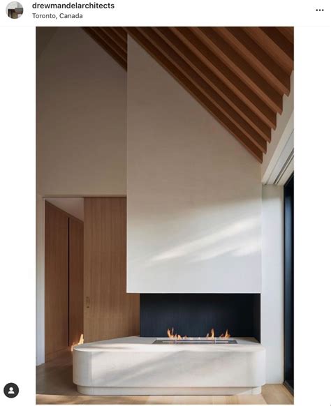 A Fireplace In The Middle Of A Room Next To A White Wall And Wooden Ceiling