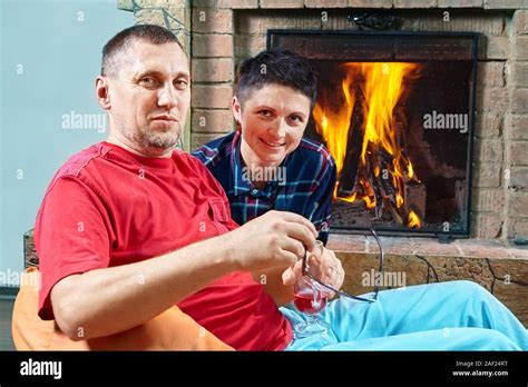 mature husband and wife are sitting on the bean bag chairs near fireplace and posing to hte