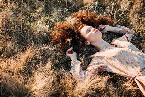 Lovely Curly Woman Enjoying Summer Sunset Laying On The Grass By Stocksy Contributor Liliya