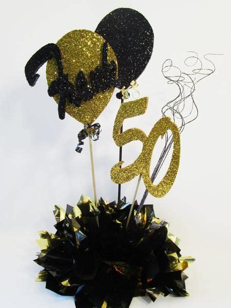 A Black And Gold 50th Birthday Cake Topper On A White Table With Some