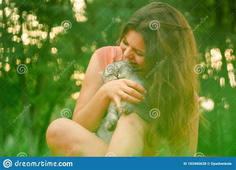 Beautiful Long Haired Brunette Girl In A Park Sitting With A Cat The Girl Growls At The Cat And