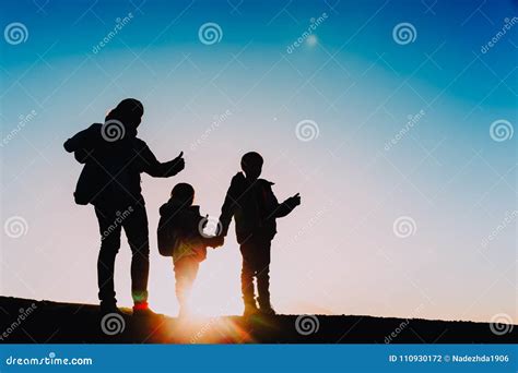 Silhouettes Of Mother With Kids Enjoy Hiking At Sunset Stock Photo