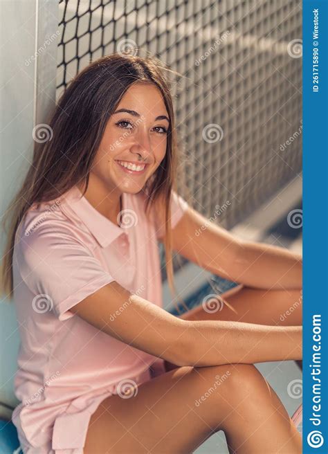 Vertical Shot Of A Young Female In Pink Athleisure Posing Sitting On A