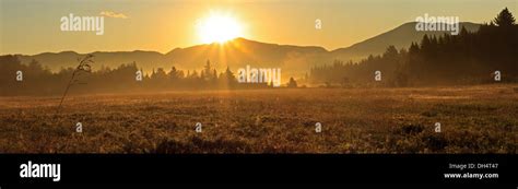 Panoramic Sunrise Image Of A Foggy Field And Mountains In The High