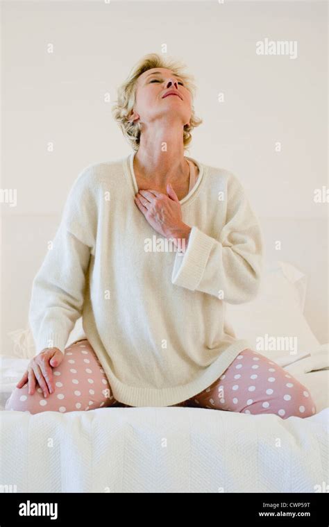 Mature Woman Kneeling On Bed Massaging Neck Stock Photo Alamy