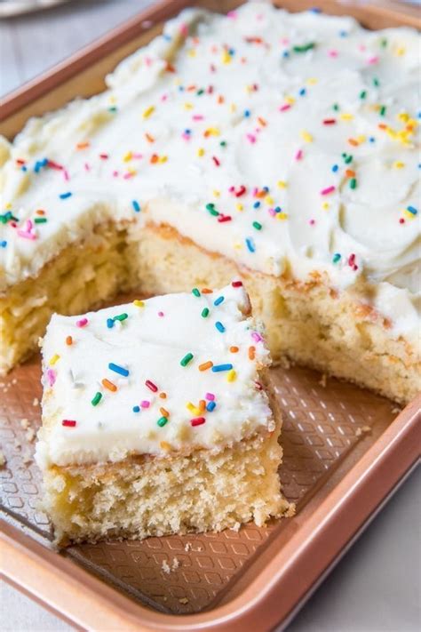 A Piece Of Cake With White Frosting And Sprinkles Sits On A Plate