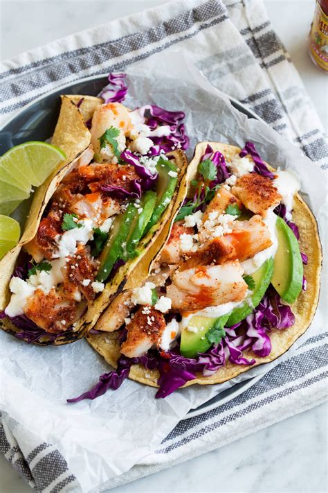 Tender and flaky fish full of spicy flavor tucked into flour tortillas and topped with garlic cilantro lime slaw. Fish Tacos - these are unbelievably delicious! Easy to ...