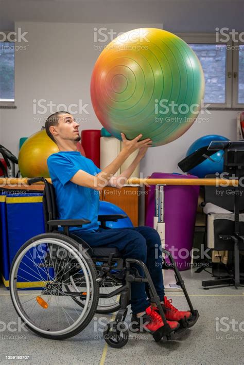 A Real Disabled Skinny Young Man And Wheelchair Lifts Weights And A