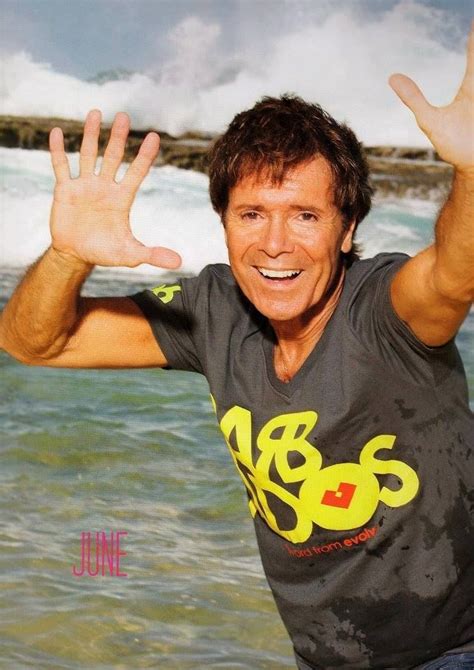 A Man Is Standing In The Water With His Hands Up And Smiling At The Camera