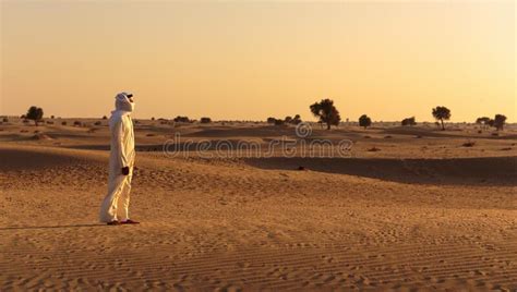 Arab Man Stands Alone In The Desert And Watching The Sunset Stock Photo