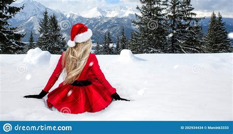 merry christmas beautiful blonde woman in red dress and santa clause hat on a background of