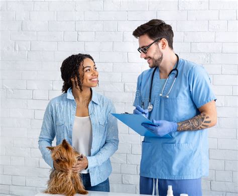 Dog Owner With Her Cute Pet Communicating To Veterinary Doctor At