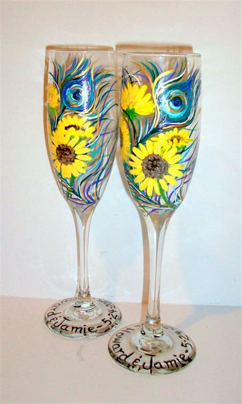 Two Wine Glasses Decorated With Sunflowers And Peacock Feathers Are Sitting Side By Side