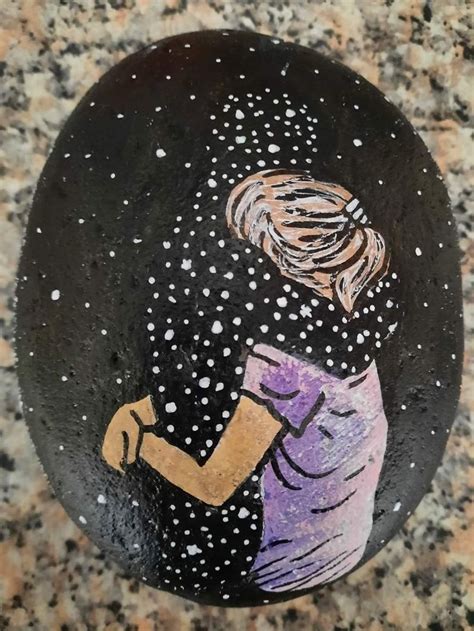 A Painted Rock With A Drawing Of A Woman Holding Her Hand Over Her