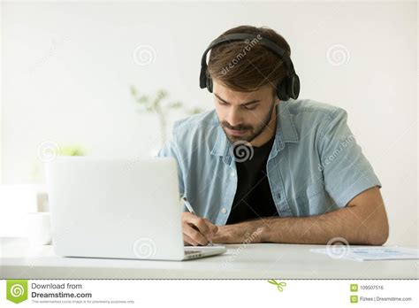 Focused Man Wearing Headphones Writing Notes Learning Online Wit Stock