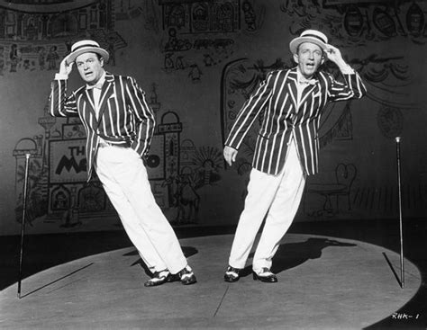 two men in striped jackets and white pants on stage