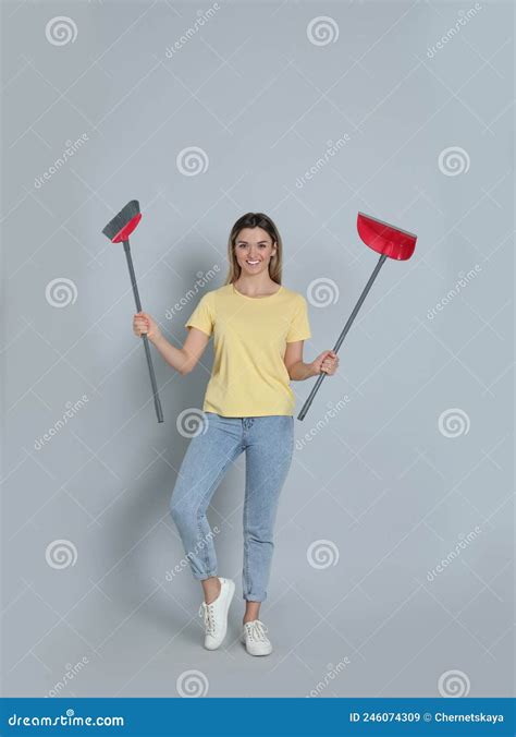 Young Woman With Broom And Dustpan On Grey Background Stock Image