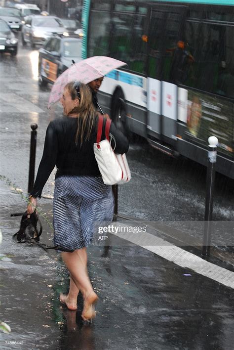 A Woman Walks Barefoot In Heavy Rain During A Summer Storm 13 June
