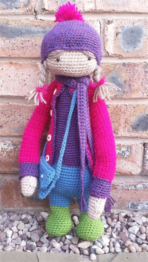 A Crocheted Doll Sitting On Top Of A Pile Of Rocks Next To A Brick Wall