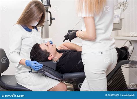 Two Female Dentists Treating Patient Teeth With Dental Tools At Dental Clinic Office Stock Image