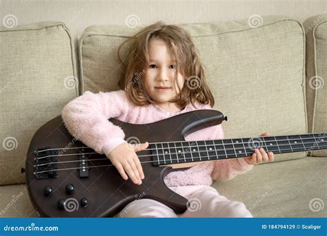 Child Playing Bass Guitar At Home Portrait Of Little Baby Girl Sitting
