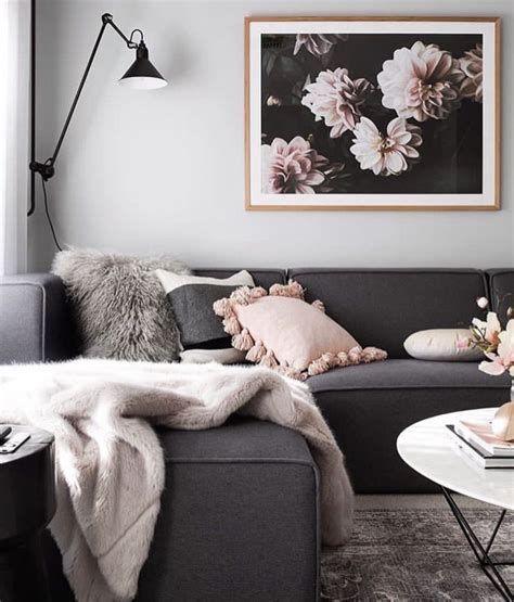 A blush pink velvet chair, complementing blush pink curtains, sits on a light gray rug at an ivory secretaire desk topped with a pink, purple, and black abstract art piece. grey , pink and and white living room | Living room decor gray, Dark grey couch living room ...