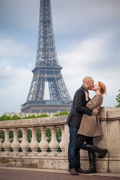 romantic couple in paris kissing eiffel tower in the background by stocksy contributor