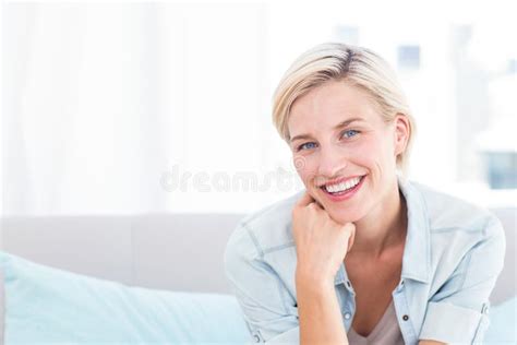 Pretty Blonde Woman Sitting On The Couch And Smiling At The Camera