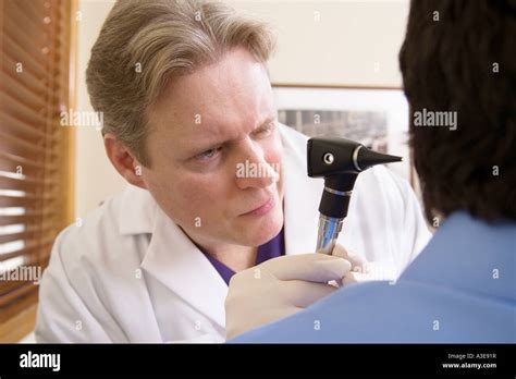 Male Physician Uses An Otoscope To Check The Ear Of His Patient During