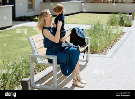 Young Mother Hugs Her Son 3 Years Old Sitting On Bench In The Park