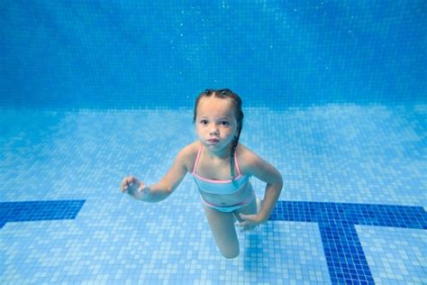Маленькая девочка плавает под водой в детском бассейне дайвинг учит