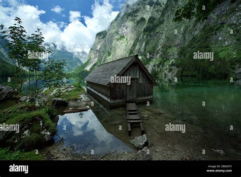 A Wooden Cabinboathouse At Obersee Lake Surrounded By Mountains In