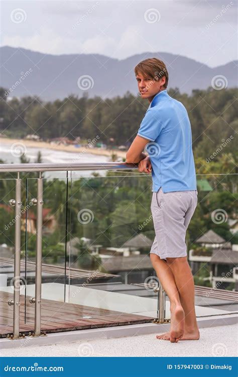 A Young Man Standing By Glass Fence On The Roof Of Hotel Stock Image