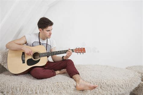 Young Man Playing Guitar While Sitting On Fur Sofa Stock Photo Image