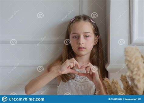 Beautiful Little Girl Shows With Gestures `I Love You`. Girl Sits On The Meadow. A Girl Shows ...