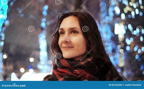 Attractive Woman At Snowy Christmas Night Smiles Looking At The Camera