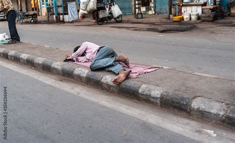 A Homeless Man Sleeping On The Street Footpath During The Day Time A