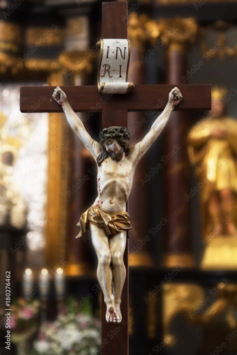 Figure Of Jesus Christ Hanging On A Wooden Cross With A Faded Altar Wreaths And Figurines Stock