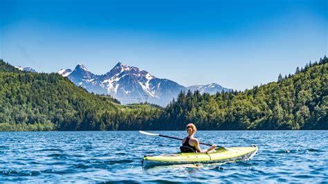 A Woman In A Kayak On A Choppy Lake With A View On Tall Snowy Mountains