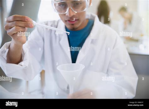Estudiante universitario masculino realizar experimentos científicos con pipeta en aula de