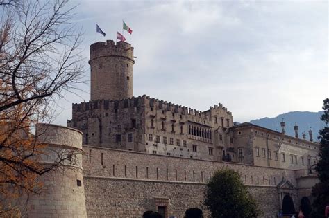 An Old Castle With Flags On Top And People Walking In The Foreground