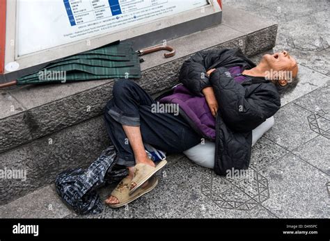 A Homeless Man Taking A Nap On A Public Sidewalk In Asakusa Tokyo