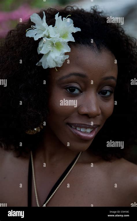 Lovely Black Woman With White Flowers In Her Hair And Looking At The Camera With A Friendly
