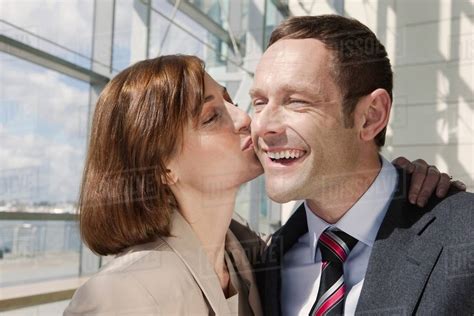 Mid Adult Couple Woman Kissing Man On Cheek Stock Photo Dissolve