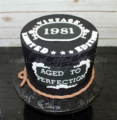 A Black And White Cake With An Aged To Perfection Sign On Its Side