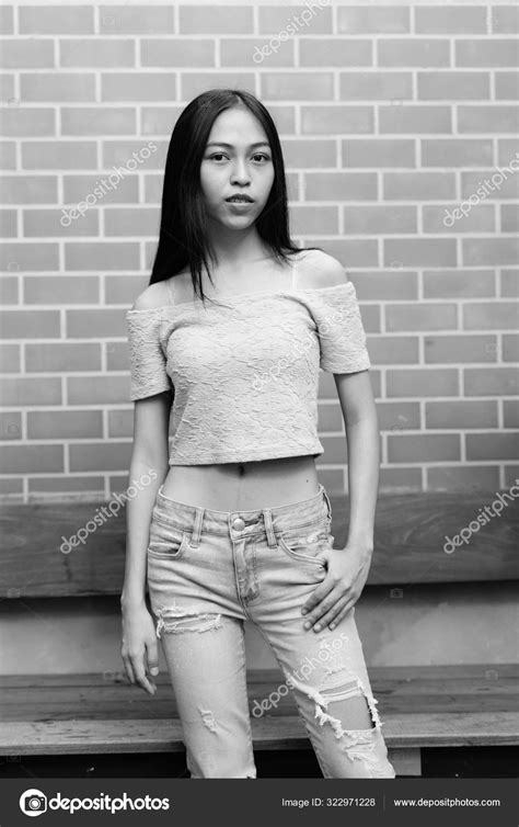 Young Beautiful Asian Teenage Girl Standing Against Brick Wall Stock