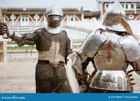 Two Medieval Knights In Full Heavy Armor Reenact A Battle On Tournament